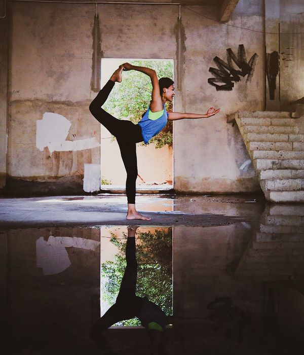 Woman in a calm yoga pose in a dark room with mint light lines.